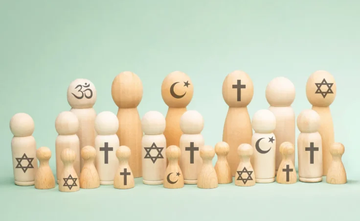 Wooden people with symbols of different religious beliefs: Christianity, Islam, Hinduism, Buddhism, and Judaism. By BeritKessler/stock.adobe.com. america religion