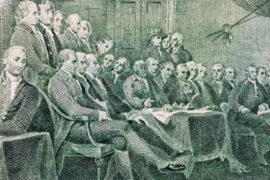 Detail of the $2 bill's reverse side, which shows the signing of the Declaration of Independence. By Sergii/stock.adobe.com. John Adams Independence Day July