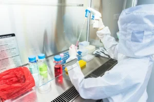 A scientist in a sterile coverall gown doing biological research. By warut/stock.adobe.com. Cell life lab