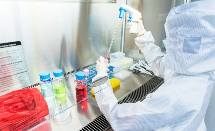 A scientist in a sterile coverall gown doing biological research. By warut/stock.adobe.com. Cell life lab