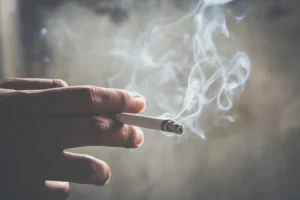 A man holding smoking a lit cigarette. By methaphum/stock.adobe.com. Smoking back in vogue