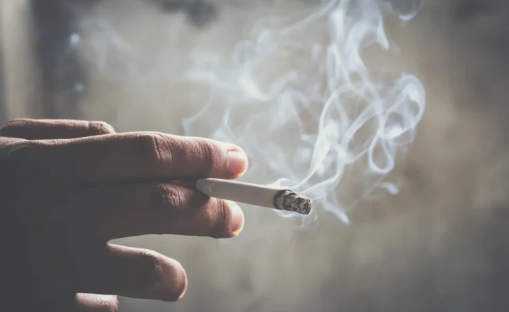 A man holding smoking a lit cigarette. By methaphum/stock.adobe.com. Smoking back in vogue